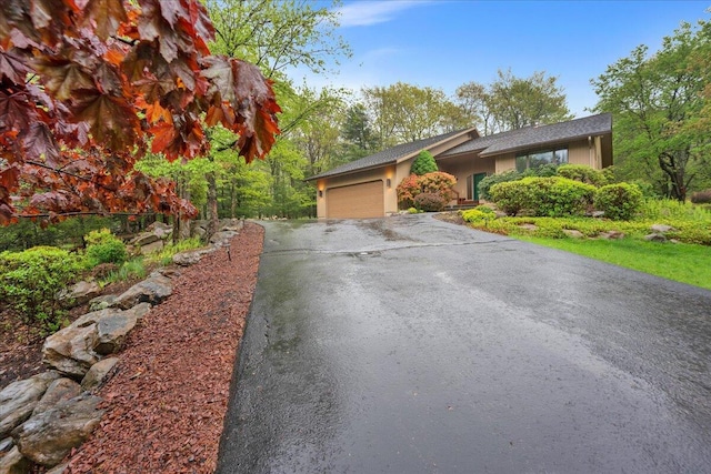 96 Wolf Hollow Rd, Lake Harmony, PA 18624 - view of front of house with asphalt driveway, an attached garage, and stucco siding