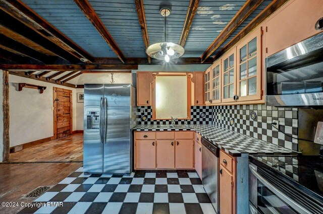 kitchen with dark floors, appliances with stainless steel finishes, decorative backsplash, and beam ceiling