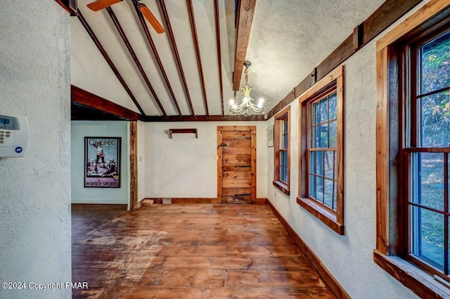 interior space featuring vaulted ceiling with beams, hardwood / wood-style flooring, baseboards, and a textured wall