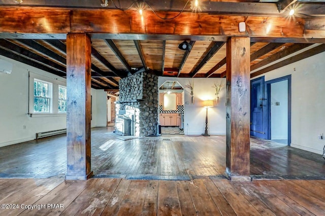 interior space with baseboard heating, wood-type flooring, a wall unit AC, and baseboards