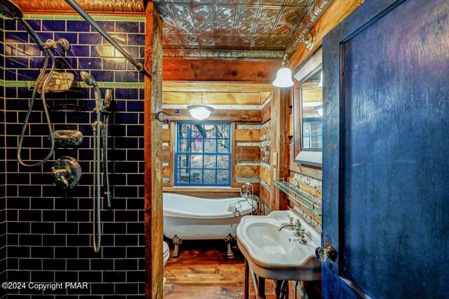 bathroom with a soaking tub, an ornate ceiling, a sink, and wood finished floors