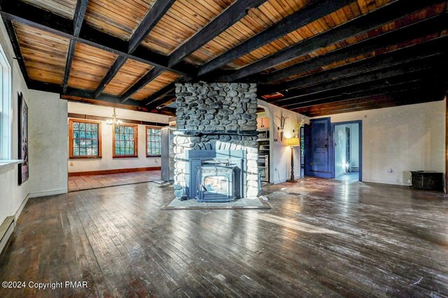 unfurnished living room with a wood stove, baseboards, wood-type flooring, and beam ceiling