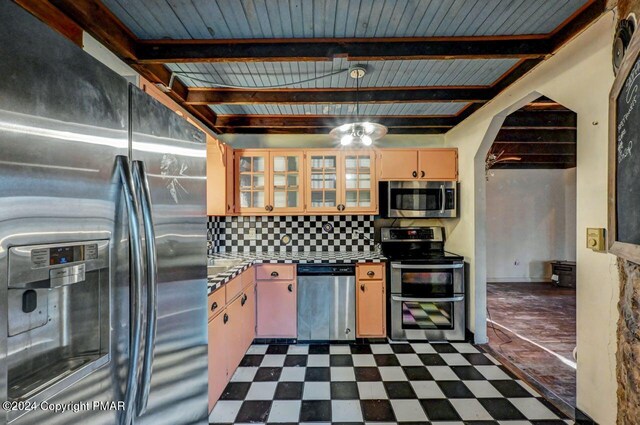 kitchen with dark floors, beam ceiling, arched walkways, tasteful backsplash, and appliances with stainless steel finishes