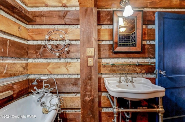 full bathroom featuring a tub to relax in, wood walls, and a sink