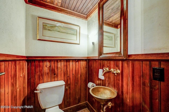 bathroom with wooden ceiling, a wainscoted wall, wood walls, and toilet