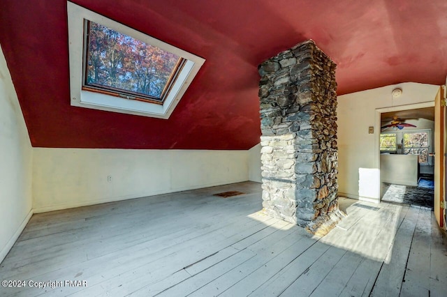 bonus room featuring a ceiling fan, vaulted ceiling with skylight, baseboards, and hardwood / wood-style floors