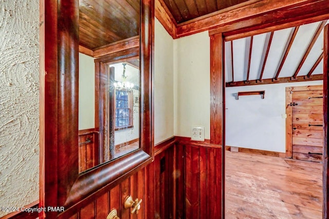 hallway with wooden ceiling, a wainscoted wall, vaulted ceiling with beams, and wood finished floors