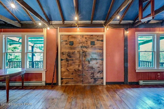 interior space featuring a baseboard heating unit, a baseboard radiator, lofted ceiling, and hardwood / wood-style flooring