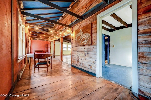 interior space with beamed ceiling, baseboard heating, and wood-type flooring