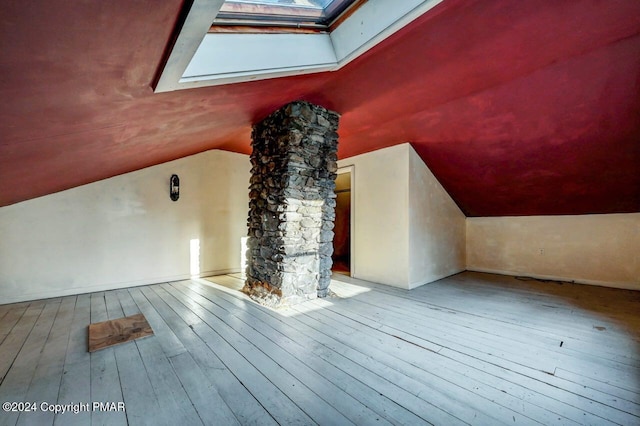 bonus room featuring lofted ceiling with skylight, hardwood / wood-style floors, and ornate columns