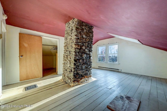 additional living space with vaulted ceiling, hardwood / wood-style floors, baseboard heating, and visible vents