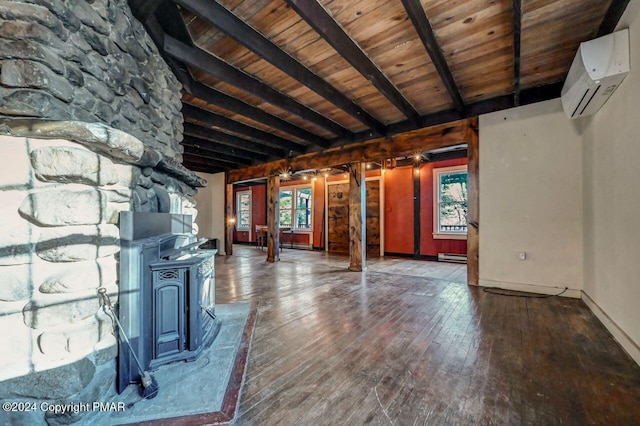 unfurnished living room with a wall unit AC, a baseboard radiator, a wood stove, wooden ceiling, and hardwood / wood-style floors