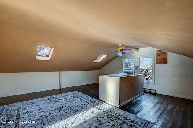 additional living space featuring lofted ceiling with skylight, dark wood finished floors, baseboard heating, and ceiling fan