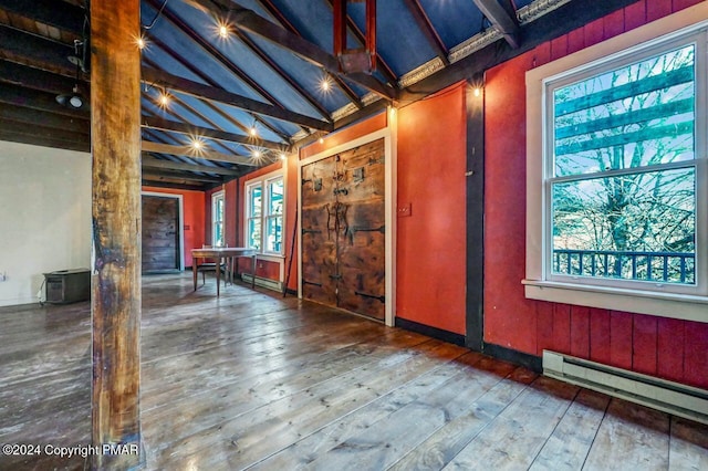 misc room with a baseboard heating unit, hardwood / wood-style floors, baseboards, and vaulted ceiling with beams