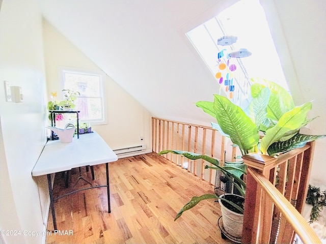 interior space with lofted ceiling, hardwood / wood-style floors, and a baseboard heating unit