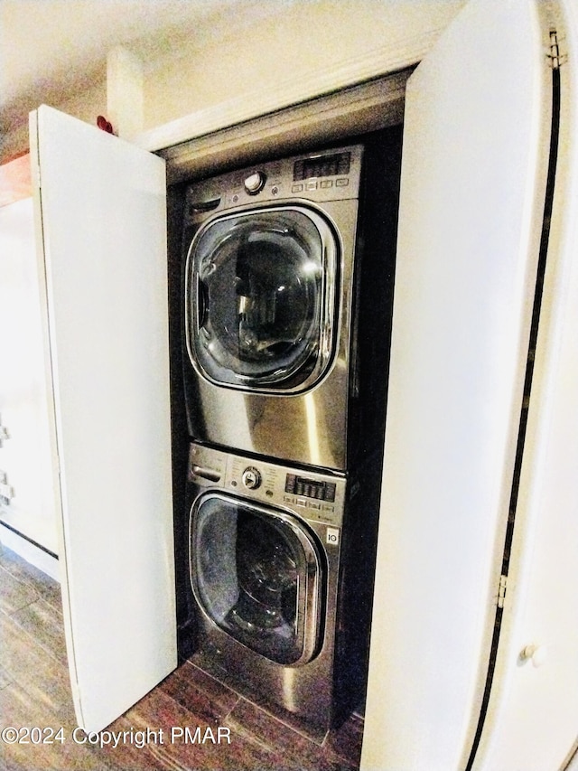 clothes washing area featuring stacked washing maching and dryer and wood-type flooring