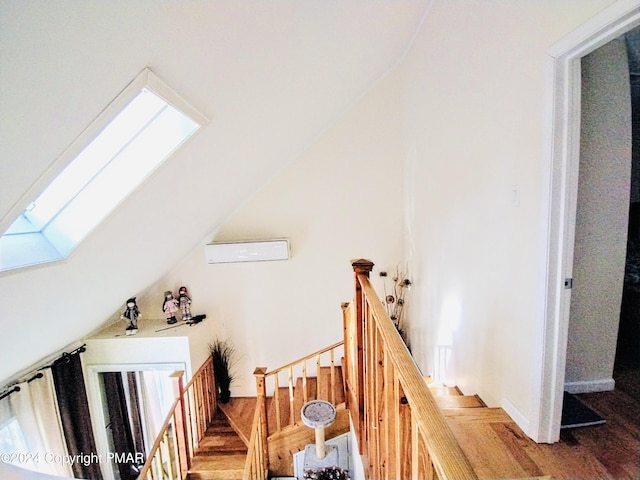 staircase with a wall mounted AC and vaulted ceiling with skylight