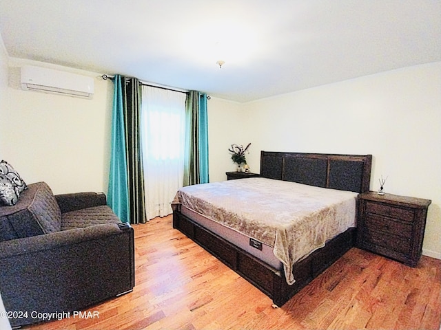 bedroom featuring a wall mounted AC and light hardwood / wood-style flooring