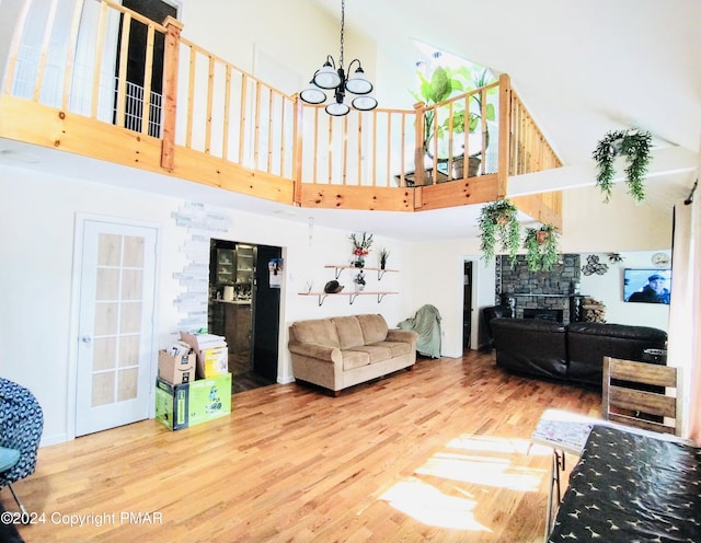 living room with wood-type flooring, a towering ceiling, and an inviting chandelier