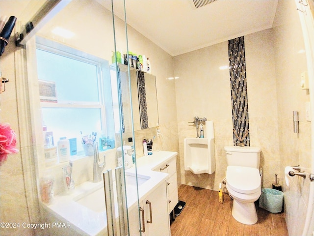 bathroom with toilet, an enclosed shower, tile walls, vanity, and hardwood / wood-style flooring