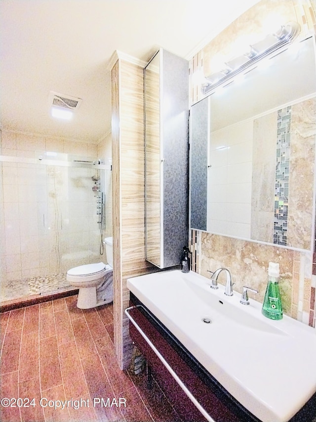 bathroom featuring walk in shower, toilet, tile walls, vanity, and decorative backsplash