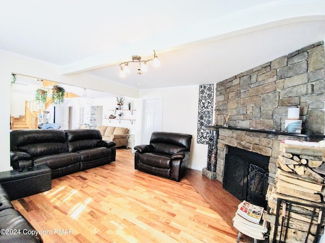 living room with beamed ceiling, a stone fireplace, and hardwood / wood-style floors