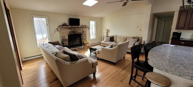 living area featuring light wood finished floors, a baseboard radiator, a fireplace, and a wealth of natural light