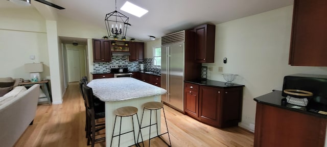 139 Eliot Ln, Albrightsville, PA 18210 - kitchen with lofted ceiling, a breakfast bar area, light wood-style floors, decorative backsplash, and a center island