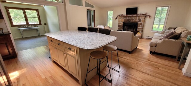 139 Eliot Ln, Albrightsville, PA 18210 - kitchen featuring a kitchen bar, open floor plan, a stone fireplace, light wood-type flooring, and a baseboard radiator