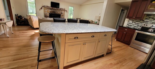 139 Eliot Ln, Albrightsville, PA 18210 - kitchen with electric range, a breakfast bar area, light wood-style flooring, decorative backsplash, and vaulted ceiling