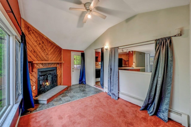 159 Sandstone Dr, Dingmans Ferry, PA 18328 - unfurnished living room with a baseboard heating unit, vaulted ceiling, a lit fireplace, ceiling fan, and carpet