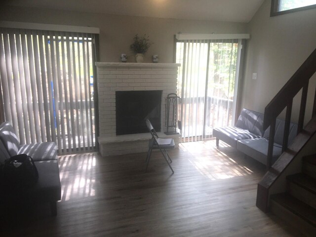 1148 Country Place Dr, Tobyhanna, PA 18466 - living room with healthy amount of natural light, stairway, lofted ceiling, wood finished floors, and a brick fireplace