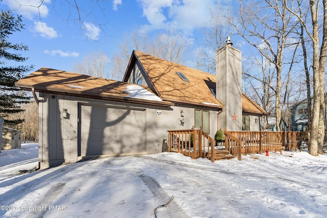 exterior space featuring a garage, roof with shingles, a chimney, and a wooden deck