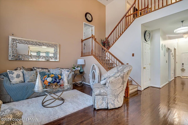 living area with stairs, wood finished floors, a towering ceiling, and baseboards