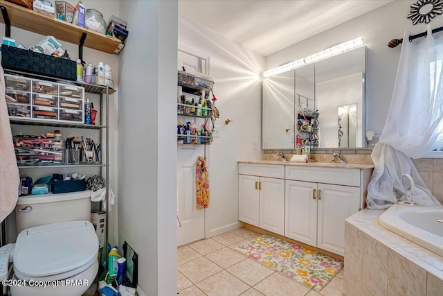 bathroom with tile patterned flooring, toilet, a relaxing tiled tub, a sink, and double vanity