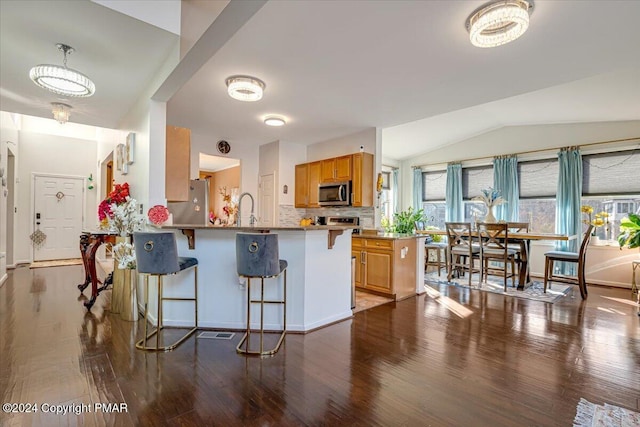 kitchen featuring stainless steel appliances, a peninsula, a kitchen breakfast bar, and wood finished floors