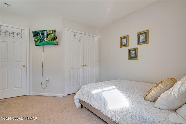 bedroom featuring baseboards, a closet, and light colored carpet