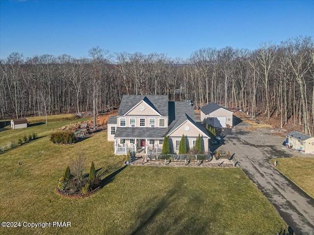 view of front of house with driveway, a porch, a forest view, and a front yard