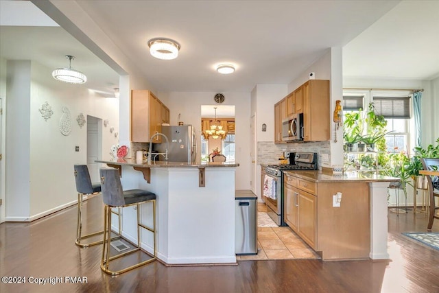 kitchen featuring stainless steel appliances, a breakfast bar, a peninsula, and tasteful backsplash