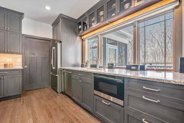115 Ridgewood Ln, Hawley, PA 18428 - kitchen with stainless steel appliances, light wood-type flooring, light stone countertops, a sink, and backsplash
