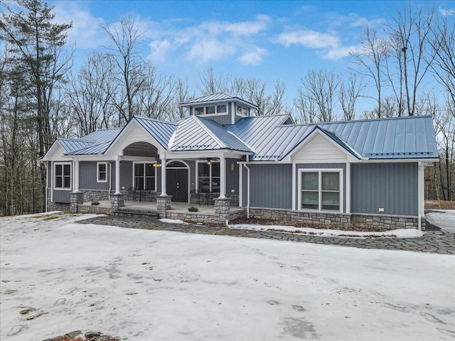 view of front of home with metal roof, a porch, a standing seam roof, and stone siding