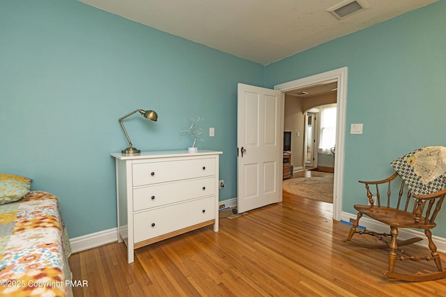 living area with light wood-style flooring, visible vents, and baseboards