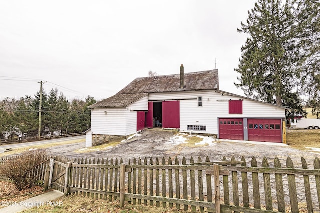 ranch-style home with an outbuilding, fence private yard, a garage, driveway, and a chimney