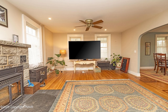 living area with arched walkways, recessed lighting, ceiling fan, wood finished floors, and baseboards