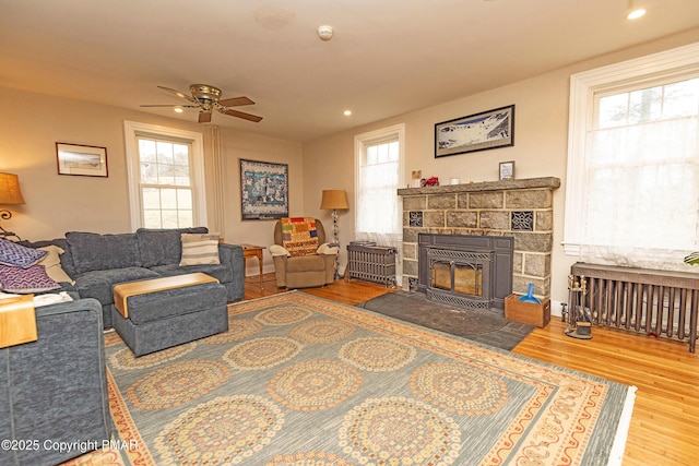 living area featuring a fireplace, a ceiling fan, wood finished floors, and recessed lighting