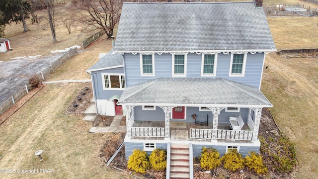 view of front of property featuring covered porch, stairs, a front lawn, and roof with shingles