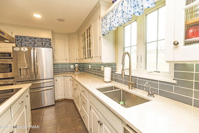 kitchen with stainless steel appliances, tasteful backsplash, sink, and white cabinets