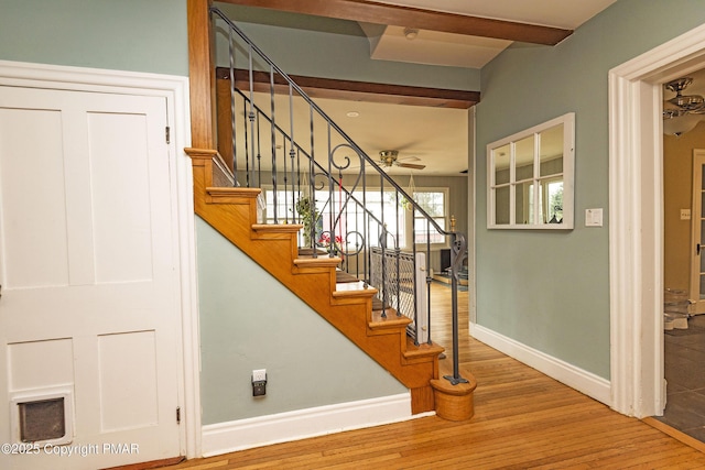 stairway with ceiling fan, baseboards, and wood finished floors