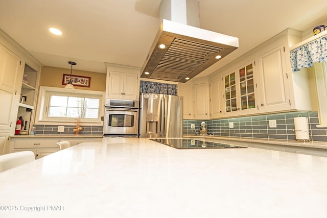 kitchen with white cabinets, appliances with stainless steel finishes, range hood, light countertops, and backsplash