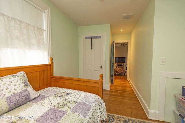 bedroom with a walk in closet, wood-type flooring, and a closet